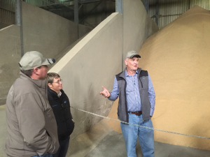 Man Standing Next to Grain Around Three People