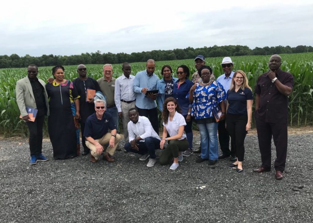 image of a group of people smiling for a photo in front of a corn field