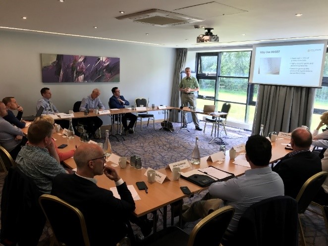 Ireland DDGS- team seated in a meeting listening to a man's presentation