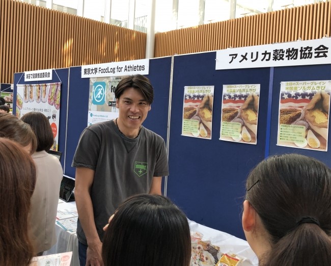2019 Japanese Food Sorghum Promotion- man standing at a booth speaking to 2 ladies