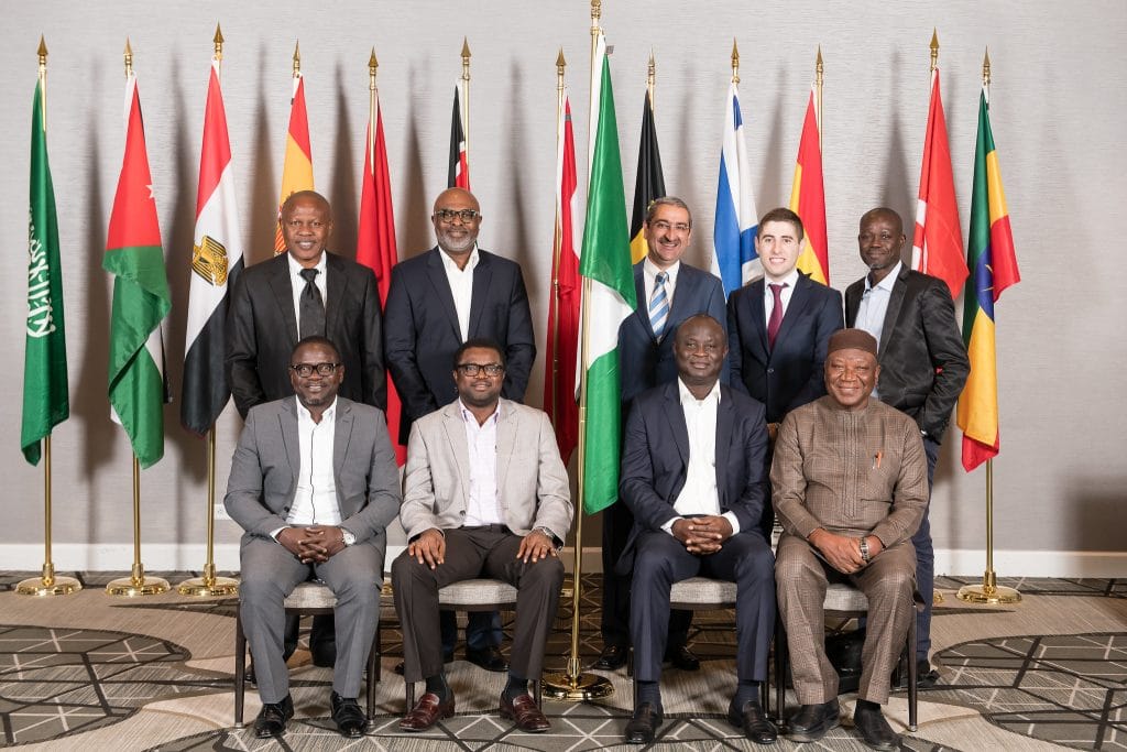 9 People Standing and Sitting in Front of Flags