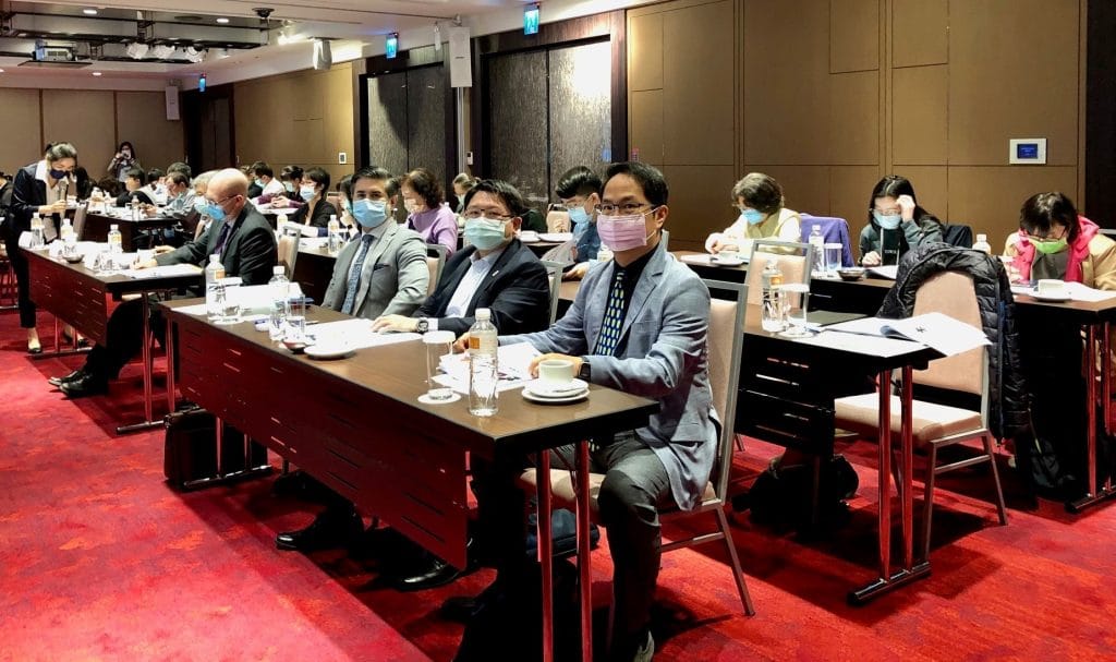 Three Rows of People Sitting at Desks With Red Carpet