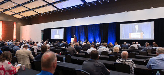 Meeting room with people watching presentation on screens.