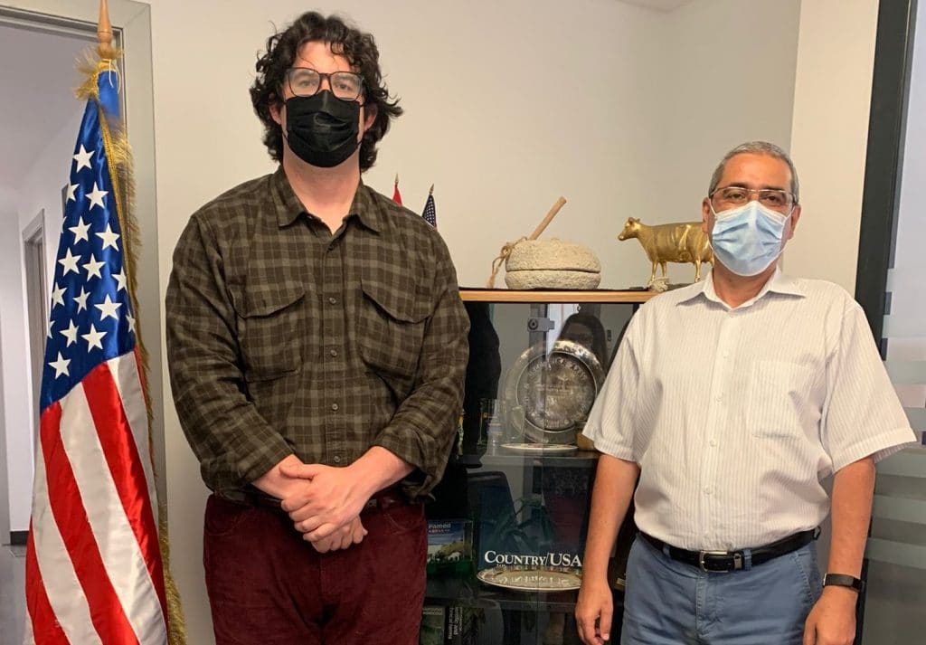 Two Men Standing Side by Side Next to Flag