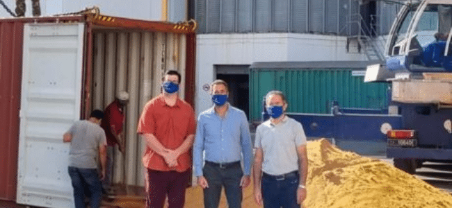 image of three men standing in front of DDGS pile