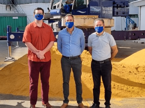 Three men next to a DDGS pile