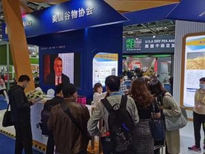 A group of people gather around a booth to at a trade show.