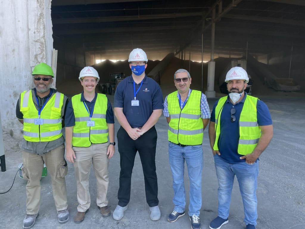 Group of men in safety vests and hard hats standing together.