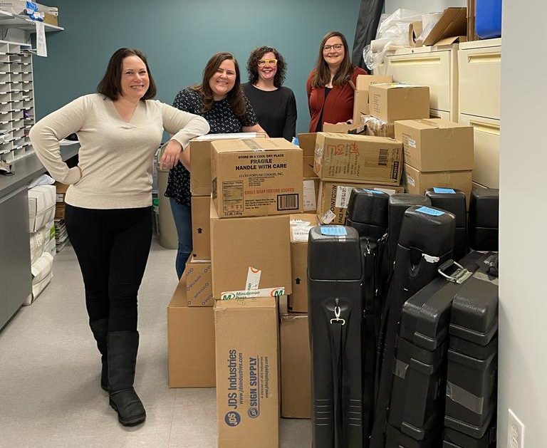 four women standing with boxes
