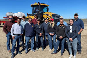 a group of people smiling for a photo in front of a tractor