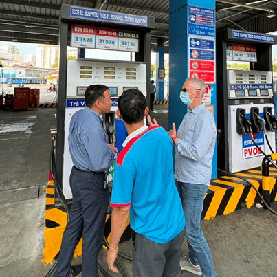 3 men talking at a gas pump