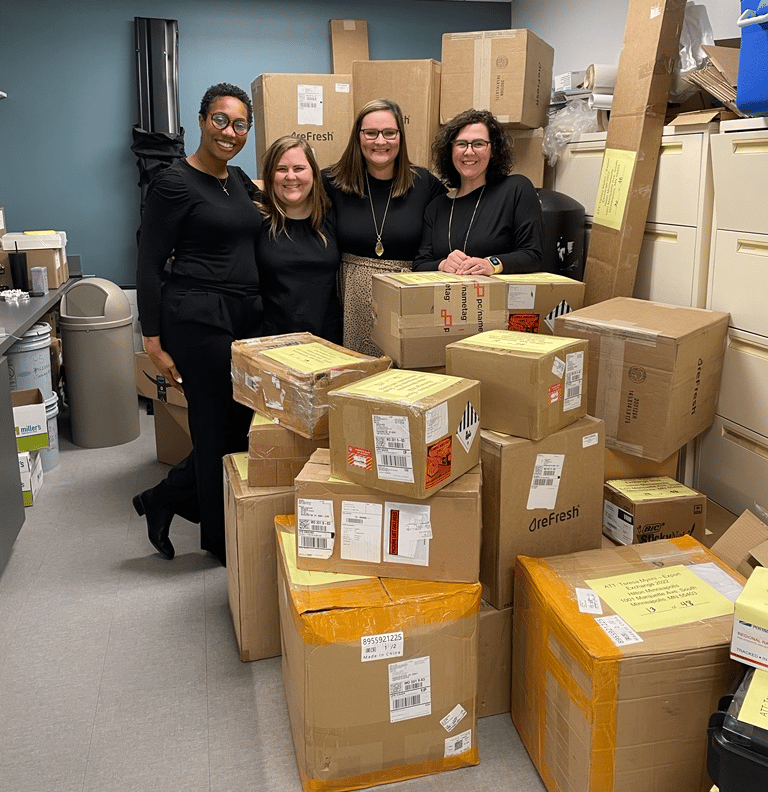 image of four women standing with boxes