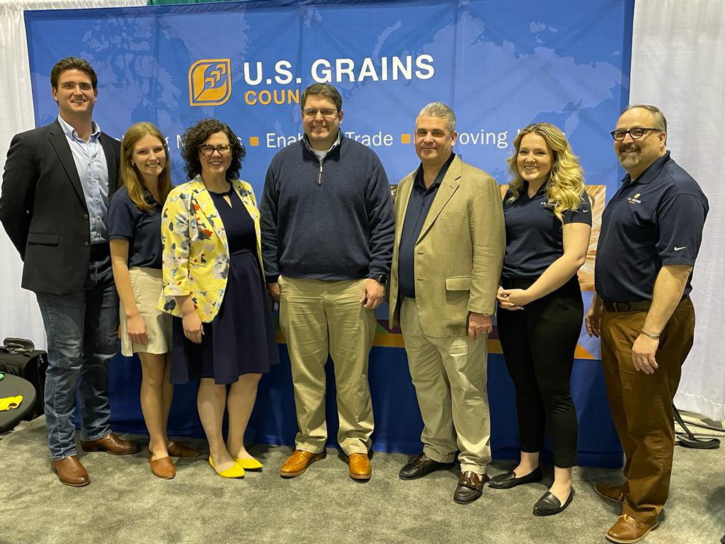Image of 7 people smiling for a photo at a trade show