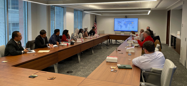 image of people listening to a presentation at a conference room table