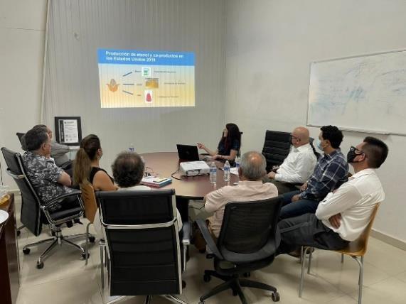 A group of people sitting at a table looking at a slideshow