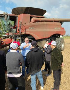 People standing in a field with farm equipment